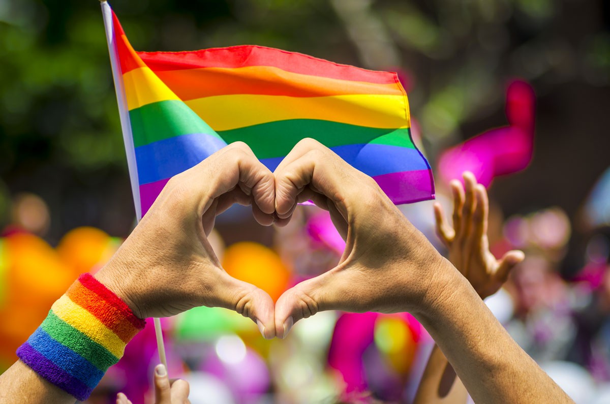 mains devant drapeau arc en ciel